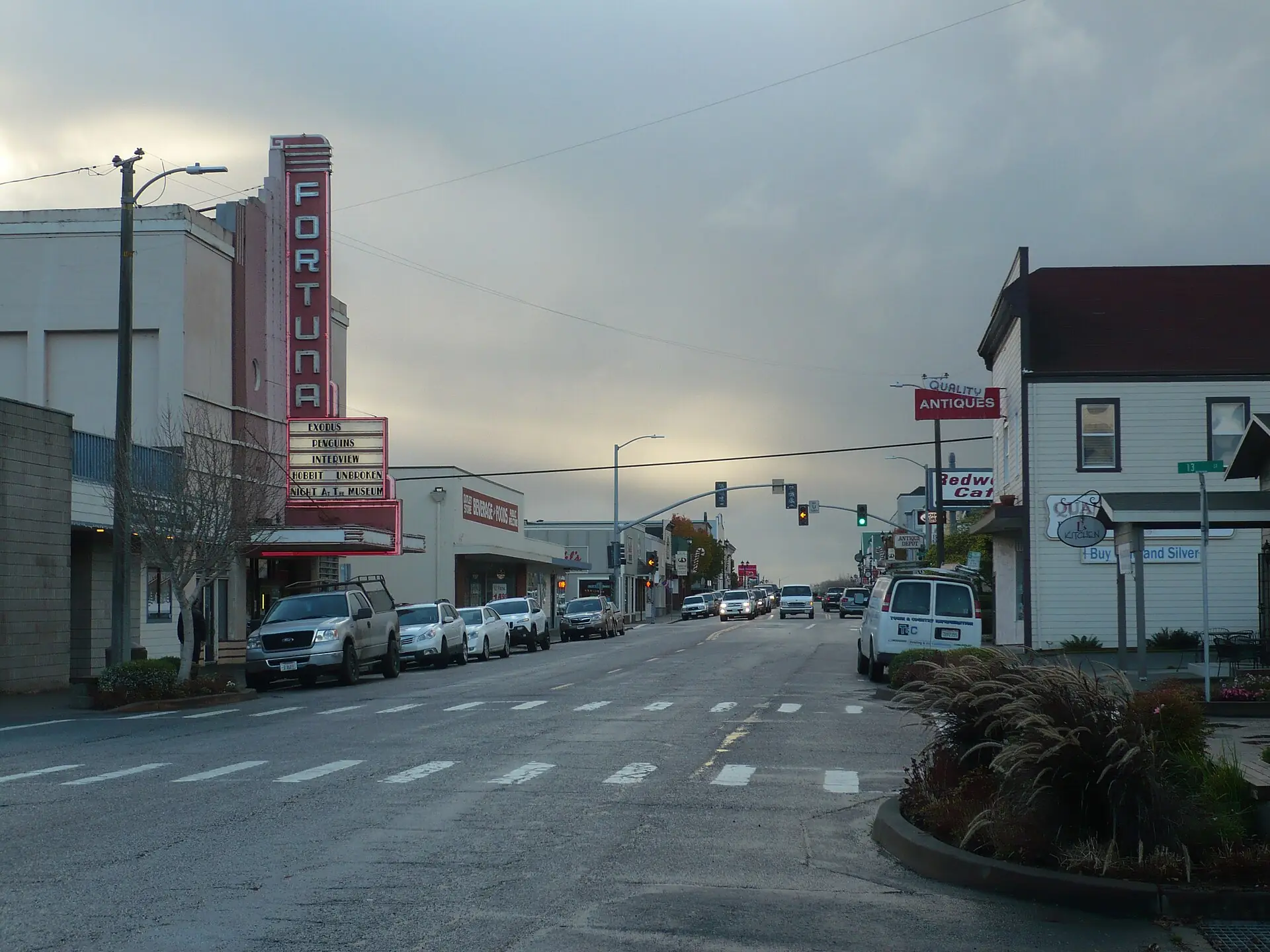 The neon marquee of the Fortuna Theatre on Main Street at dusk, with shops and traffic signals down the block