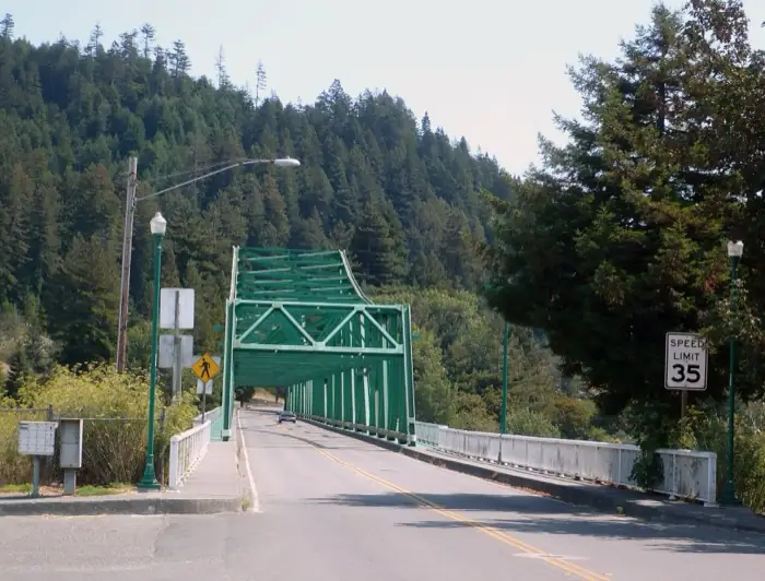 The green steel truss of the Eagle Prairie Bridge carrying the road into Rio Dell, redwood hills rising behind